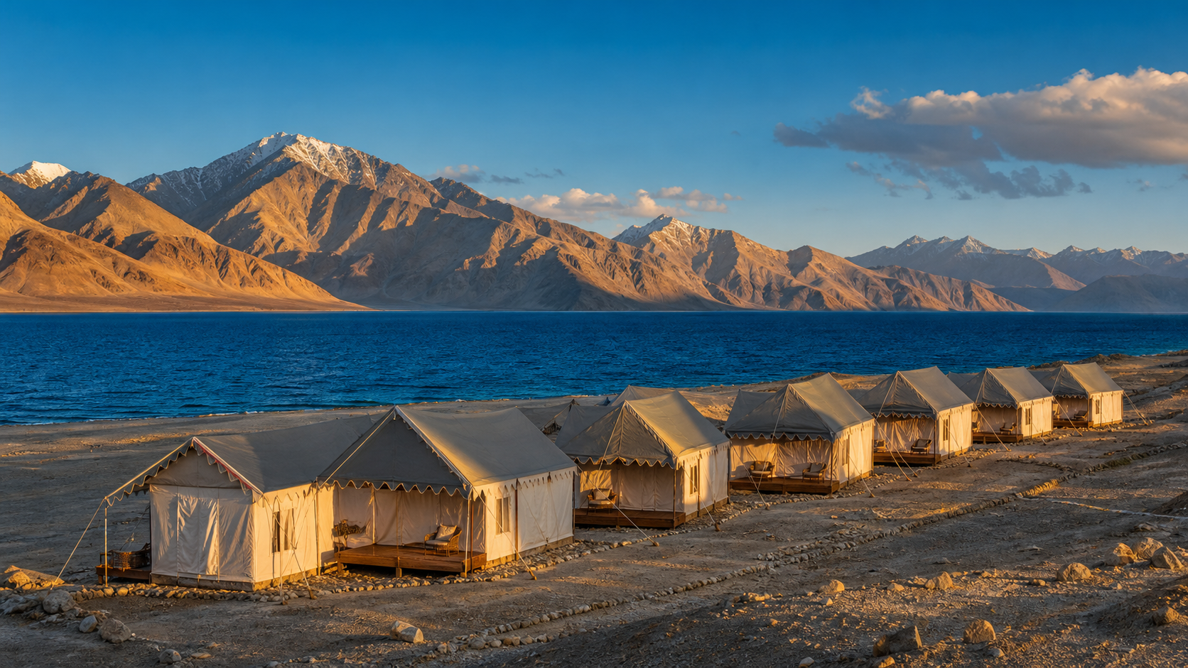 Pangong Lake at sunrise with mountains and lakeside camps